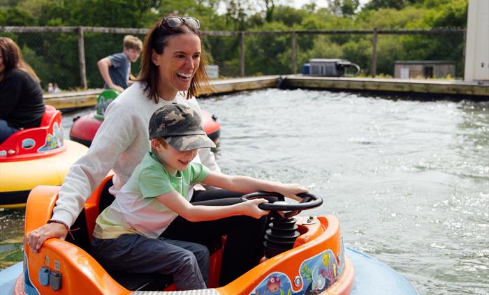 A mother and son having fun on the big disco boats, which are being driven on water.